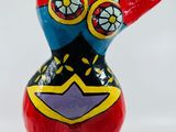 figurine en céramique représentant une femme en robe rouge et chapeau bleu, posée sur un socle noir