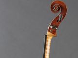 an old violin sitting on top of a wooden stand on a gray surface