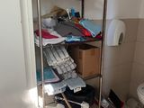 a bathroom with a toilet and a shelf full of cleaning supplies