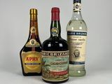 trois bouteilles d'alcool sont alignées sur une surface blanche