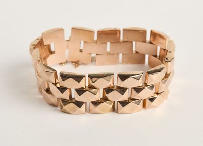 gros plan d'un bracelet en or sur une surface blanche