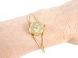 a woman ' s arm with a gold bracelet and a watch on it