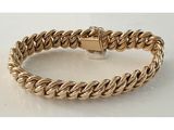 gros plan d'un bracelet en or sur une surface blanche