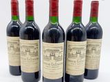 quatre bouteilles de vin rouge posées les unes à côté des autres sur une surface blanche