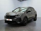 Une voiture grise est garée dans une grande pièce aux murs blancs.