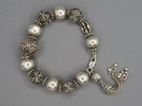 bracelet en argent orné de perles et d'une breloque en forme de couronne sur fond gris