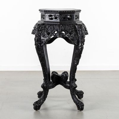 an ornate black table with a marble top on a grey floor