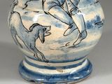 a blue and white vase with a drawing of a man riding a horse