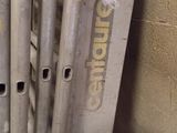 Dans une pièce, des tuyaux métalliques sont empilés contre un mur