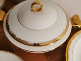a wooden table topped with white and gold china