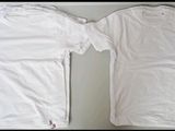 two white t - shirts sitting on top of a table next to each other
