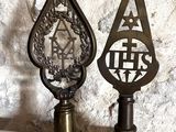paire de trophées anciens en laiton posés sur des socles en bois, avec un mur en pierre en arrière-plan