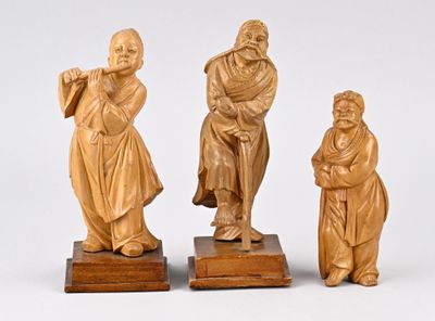 trois figurines en bois sculpté représentant un homme et une femme assis sur un banc