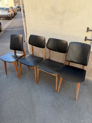 four black leather chairs are lined up against a wall in a parking lot