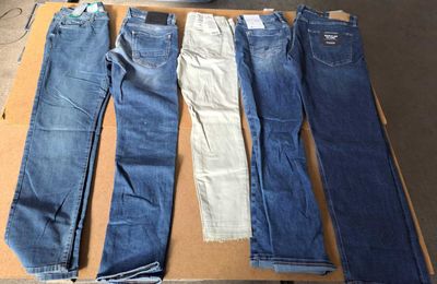 cinq paires de jeans posées sur une boîte en carton