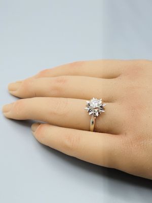 la main d'une femme à laquelle est passée une bague de fiançailles sertie d'un diamant