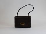 un sac à main noir avec un fermoir doré sur fond blanc