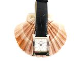 a watch sitting on top of a shell on a white surface