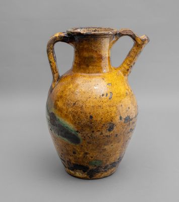 yellow and black vase with handles on a gray surface