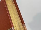 someone is holding a book in their hand and it ' s on a table