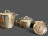 three pots and pans that are sitting on a table