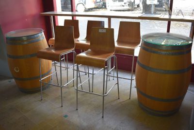 quatre chaises et une table dans une pièce où se trouvent de nombreux fûts de vin