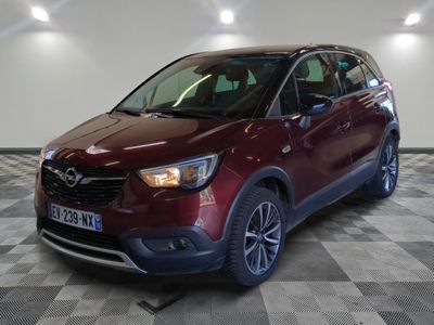 L'Opel rouge est garée dans une grande pièce au sol carrelé.