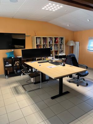une pièce équipée d'un bureau, de chaises et d'une télévision