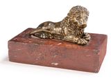 statue of a lion resting on a red marble block