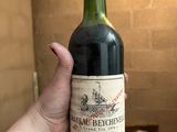 quelqu'un tient une bouteille de vin à la main dans une pièce remplie de cartons