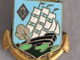 a gold and blue pin with a ship on it