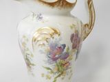 a white vase with flowers on it on a white surface