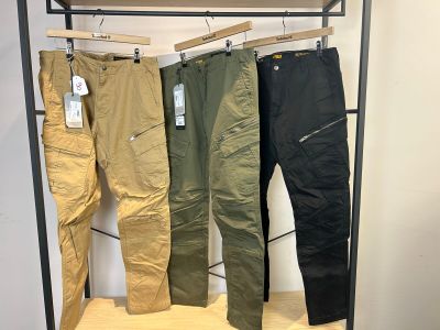 trois paires de pantalons pour hommes suspendues à un portant dans un magasin de vêtements