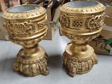 two gold vases sitting next to each other on the floor