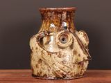 a brown vase sitting on top of a wooden table