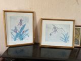 two framed pictures sitting on a table next to each other