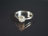 une photo d'une bague en diamant posée sur une surface noire