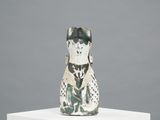 ceramic figurine of a dog on a pedestal with a gray background