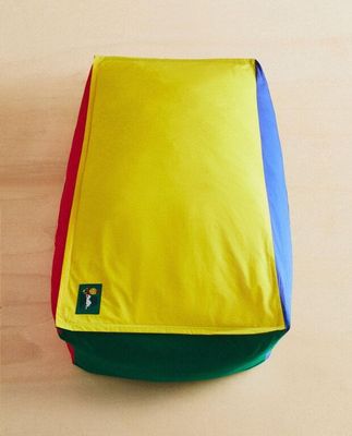 un coussin jaune, bleu, rouge et vert posé par terre