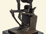 statue représentant un squelette assis sur une caisse, un couteau à la main