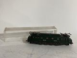 un petit train posé sur une surface blanche, avec une boîte en arrière-plan