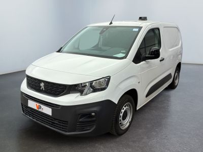 La camionnette blanche est garée dans une grande pièce au sol noir.