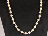 a white pearl necklace on a black mannequin