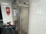 un réfrigérateur en acier inoxydable dans une cuisine, avec une poubelle placée devant