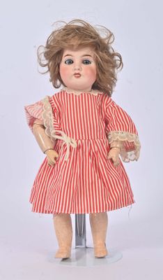 une poupée à l'ancienne, vêtue d'une robe rayée rouge et blanche et de chaussures rouges