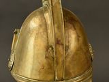 an antique helmet on a metal stand against a black background
