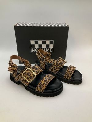 a pair of leopard print sandals in front of a box