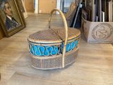 a wicker basket sitting on a table with a painting in the background