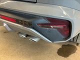 the rear end of a silver sports car parked in a garage