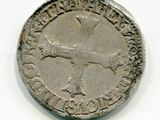 une vieille pièce d'argent sur laquelle figure une croix sur un fond blanc